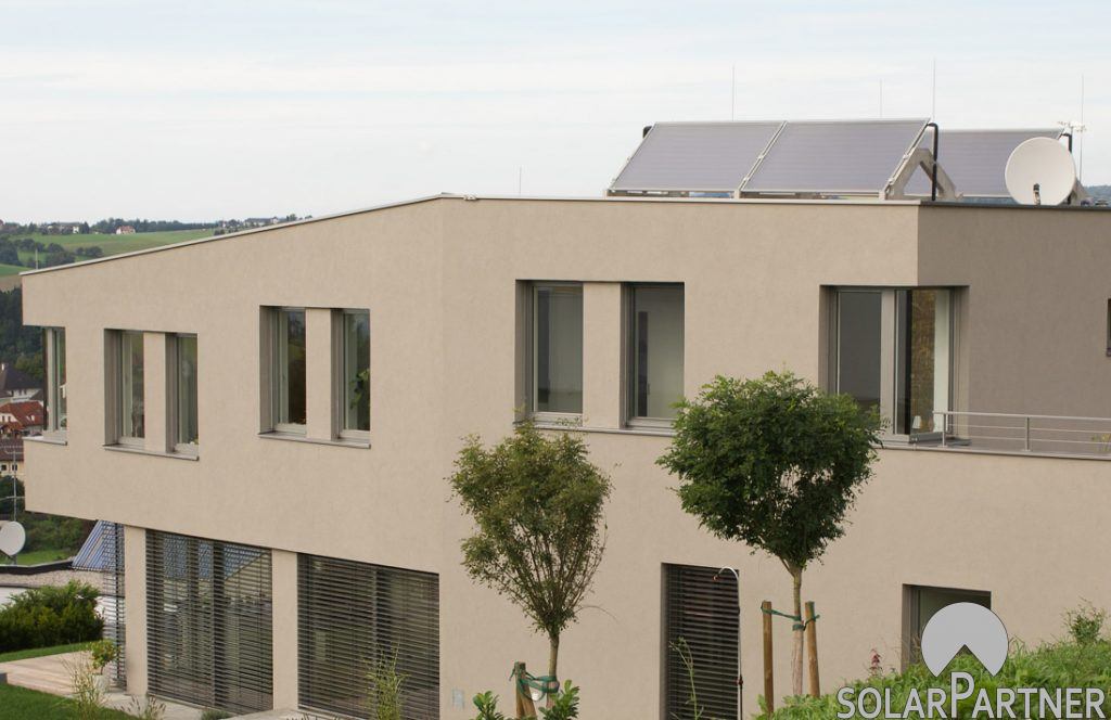 Thermische Solaranlage auf einem Wohngebäude mit Flachdach.